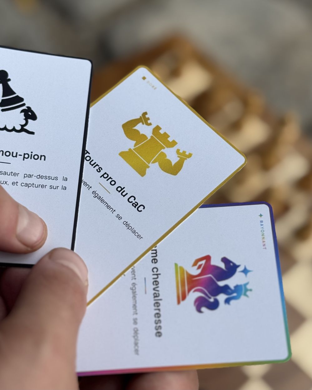 Main tenant trois cartes Jumble Chess : Saute mou-pion, Tours pro du CaC et Dame chevaleresse