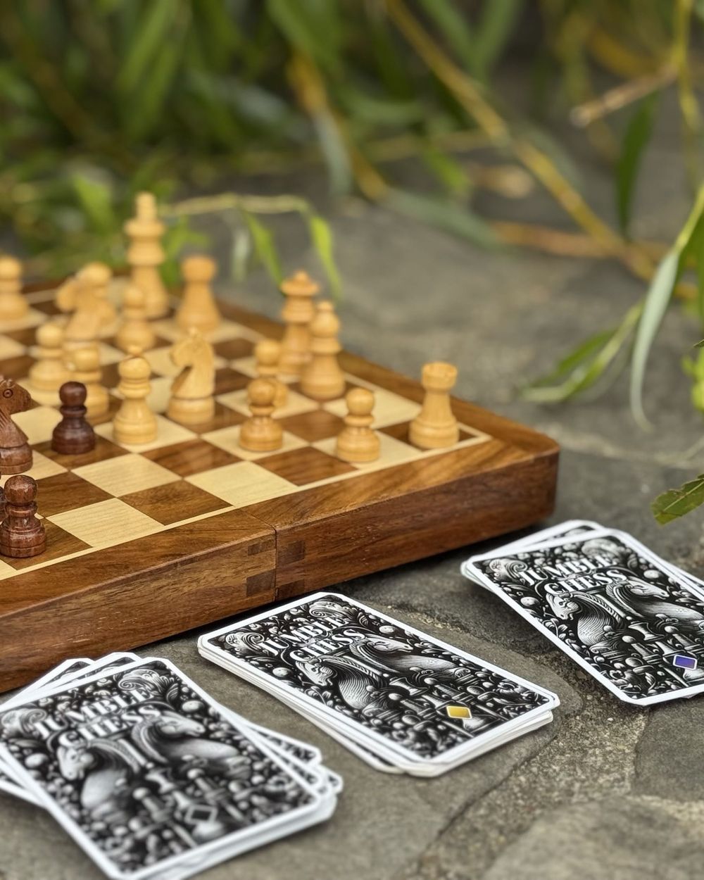 Trois piles de cartes Jumble Chess à côté d’un échiquier en bois