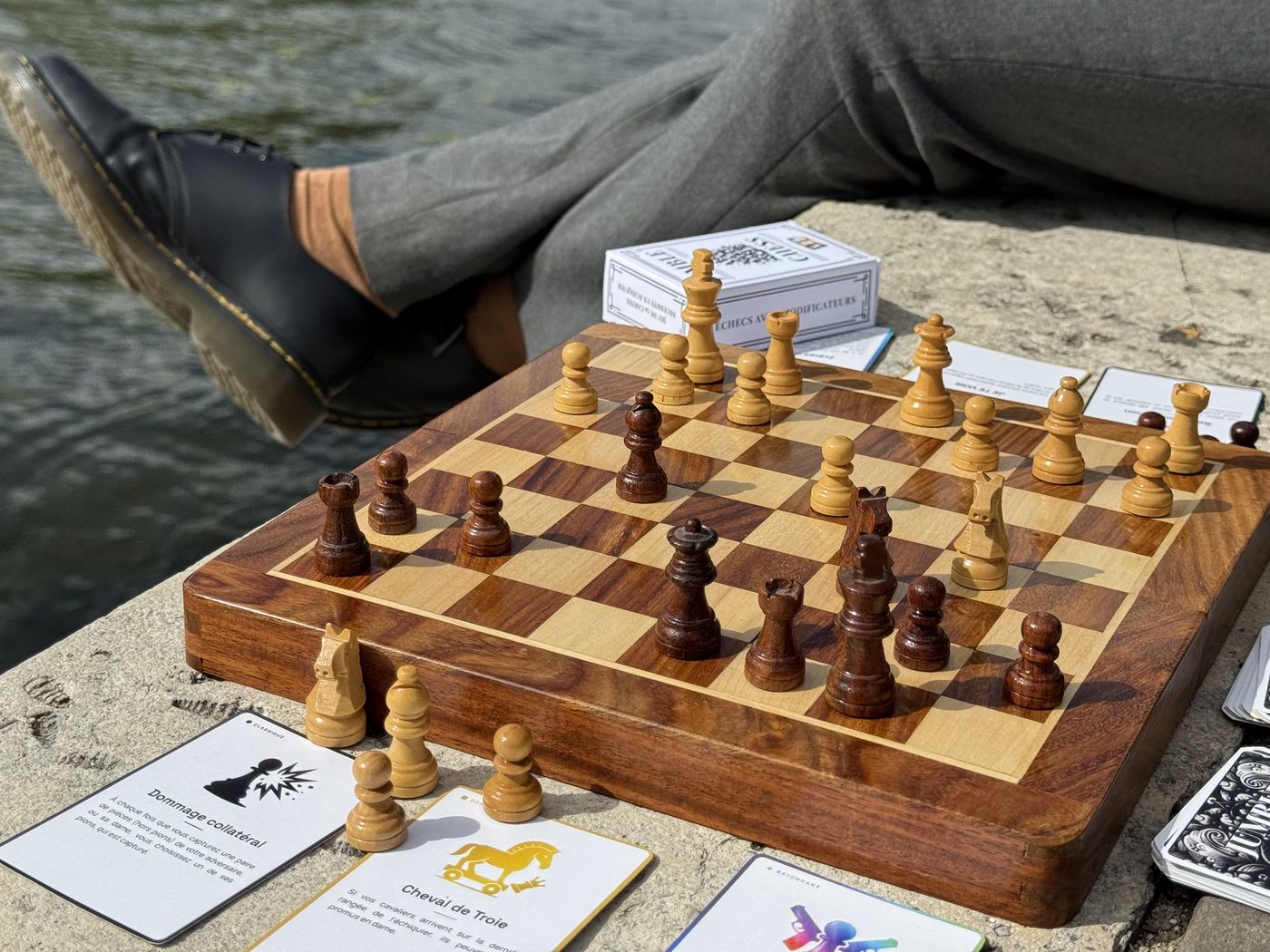 Partie de Jumble Chess en plein air au bord de l’eau, cartes modificateurs autour de l’échiquier